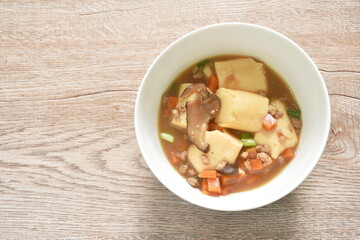 fried egg tofu with chop pork topping slice mushroom in sweet and sour gravy sauce on bowl