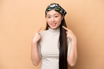 Young Chinese woman isolated on beige background giving a thumbs up gesture