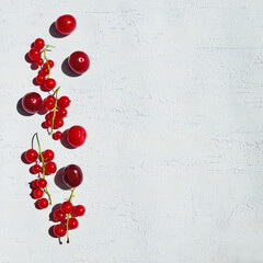 Fruit composition of red currants and cherries on a textured light background. Minimalistic summer fruit idea with space for text.
