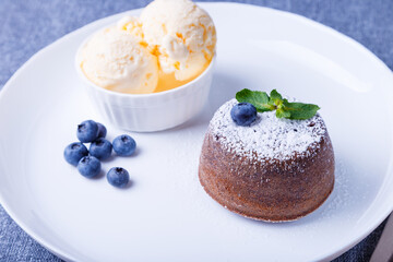 Lava cake - chocolate fondant cake with vanilla ice cream, blueberries and mint. Traditional French pastries. Close-up.