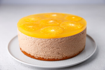 Chocolate-orange mousse cake with biscuit base, jelly and orange circles. Whole homemade cheesecake. Traditional holiday dessert. Selective focus, close-up.