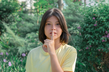 Fototapeta na wymiar A teenage girl raised her finger to her mouth.