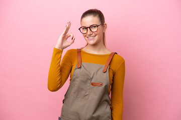 Woman with apron isolated on pink background showing ok sign with fingers