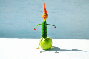 Vegetable figurine: cucumber, potato, carrot, parsley stalks, currant berries, apple. Summer healthy food concept.