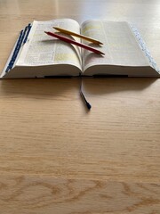 Open Bible flat lay on wooden floor with pencils, highlights and notes. Bible Study. Baselland, Switzerland - 01.07.2022