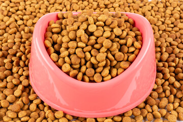 Pink bowl with dry food for a cat (dog) close-up. Balanced nutrition of pets.