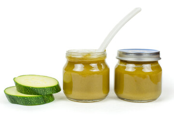 Baby food. Two glass jars with baby squash puree (zucchini) and a spoon on a white insulated background.