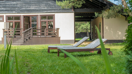 Lounge chairs on the backyard in a beautiful garden. Two empty sunbeds on the grass.