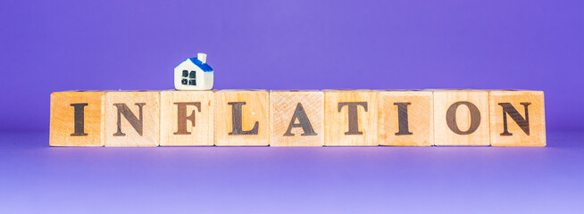 Banner Inflation symbol. Wooden cubes,miniature toy house.Beautiful purple,veri peri background. Business, inflation concept.