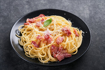 Carbonara pasta. Spaghetti with pancetta, egg, parmesan cheese and cream sauce on old dark black concrete table background. Traditional italian cuisine and dish. Pasta alla carbonara. Top view.