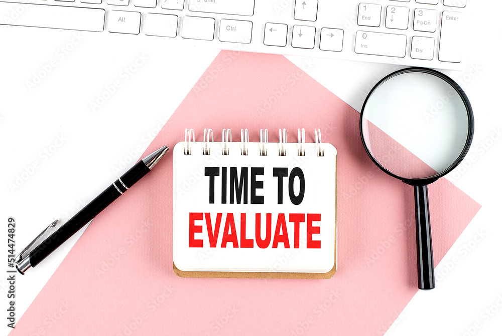 Poster business concept. notebook with text time to evaluate on pink paper with magnifier, keyboard and pen