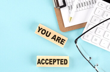 YOU ARE ACCEPTED text written on wooden block with clipboard ,eye glasses and calculator Business...