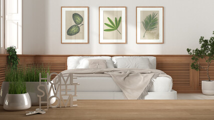 Wooden table, desk or shelf with potted grass plant, house keys and 3D letters home sweet home, over modern bedroom with white bed, architecture interior design, copy space background