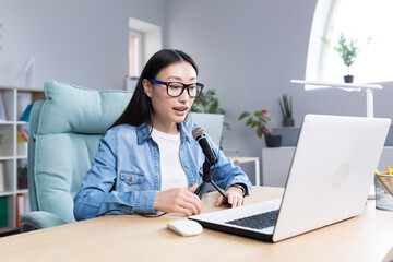 Young beautiful Asian woman recording audio podcast, woman in office using professional microphone