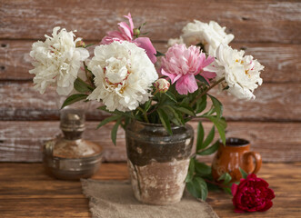 Fototapeta na wymiar Still life with white and pink peonies in a old ceramic vase on wooden background