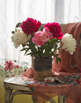 Still life with white and pink peonies in a old ceramic vase on vintaje chair