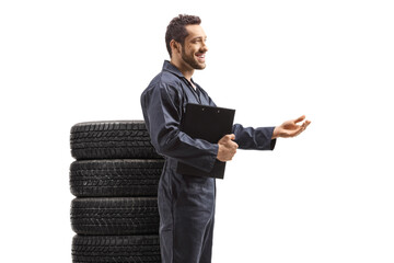 Auto mechanic with a pile of tires explaining with hand