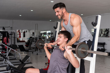 gym instructor teacher teaching a young student how to train with barbell in a gym