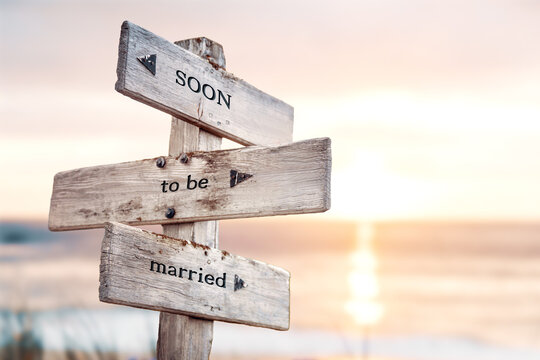 soon to be married text quote on wooden crossroad signpost outdoors on beach with pink pastel sunset colors. Romantic theme.