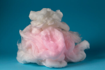 Pink cotton wool on a blue background. A soft pile of fibre.Piece Cotton wool isolated on blue