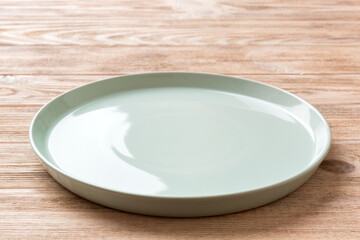 Perspective view of empty blue plate on wooden background. Empty space for your design