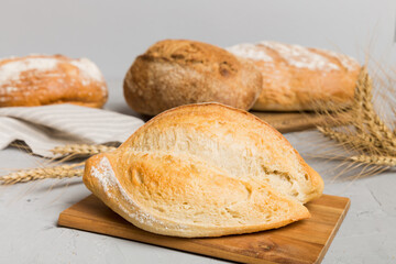 Freshly baked bread on cutting board against white wooden background. perspective view bread with copy space
