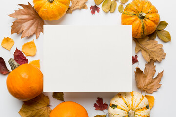 Autumn composition with paper blank and dried leaves with pumpkin on table. Flat lay, top view, copy space