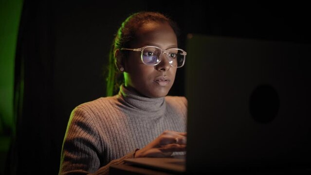 Beautiful african woman IT engineer inspecting a secure server cabinet using modern technology laptop coworking with female technician in data center.