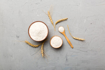 Flat lay of Wheat flour in wooden bowl with wheat spikelets on colored background. world wheat...