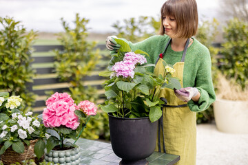 Young woman taking care of flowers in the garden. Cheerful florist or housewife replanting...
