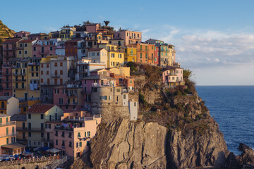 Fototapeta na wymiar Beautiful view of rocky hills and colorful historic buildings of Manarola, tourist attraction and famous place in Liguria, Italy. Hillside over the sea at sunset.