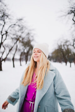 Romantic image of a young attractive woman in the winter in the park - happy emotion on a beautiful face with flowing long hair