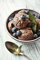 Chocolate ice cream with blueberries and fresh mint. Wooden background. Close up.