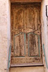 Wooded door set into a pink washed wall, decorated with blue on features of door, Corsica, France