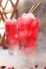 Pink homemade lemonade in glass tall glasses on the table. Cold refreshing drink with ice. Ovshala. vertical position.