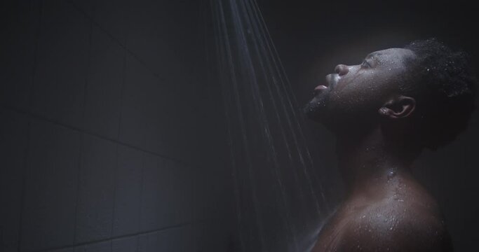 Young black male taking a shower in public shower room.