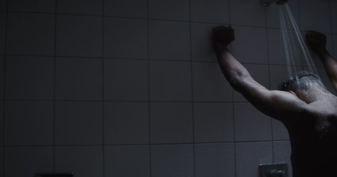 Young black male taking a shower in public gym shower.