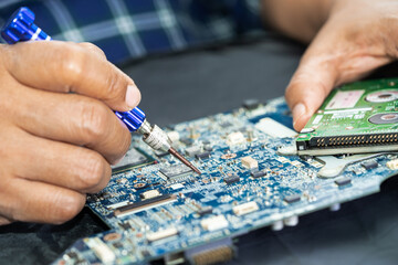 Technician repairing inside of printed circuit board PCB by soldering iron. Integrated Circuit. the...