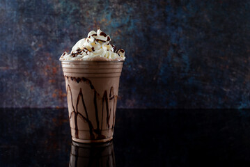 Chocolate milkshake served in a clear glass on a dark background. Isolated drink.