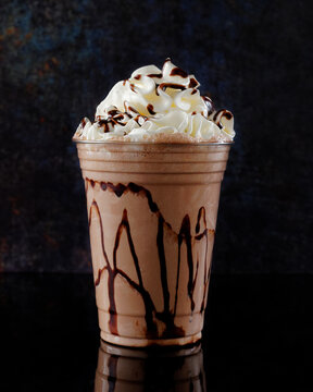 Chocolate milkshake served in a clear glass on a dark background. Isolated drink.