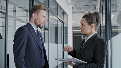 Male boss giving instructions, female employee writing in notepad, workflow