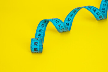 Blue tape measure diet concept on yellow background with copyspace