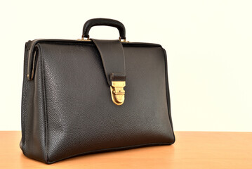 Retro black leather briefcase on the brown wooden table 