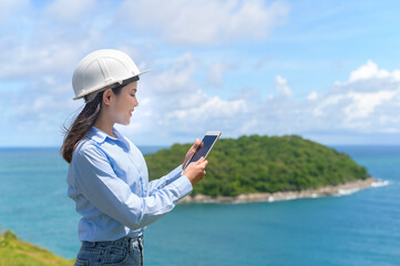 Female engineer working on the seaside wearing a protective helmet .