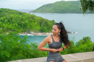 A Beautiful fit woman in sportswear exercising on seaside mountain peak, Health and Travel concept.