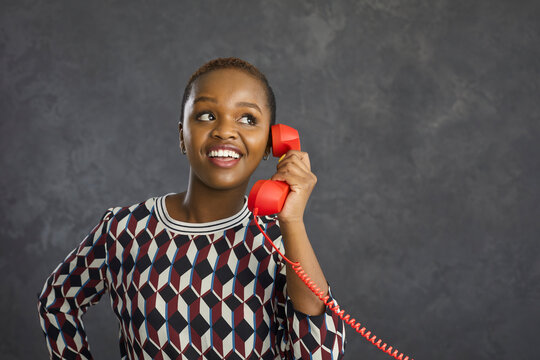 Happy young African American woman isolated on grey studio background talk speak on phone with client customer. Smiling millennial biracial ethnic female have telephone call. Communication concept.