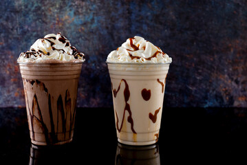 Milkshakes of different flavors in clear glass on a dark background.