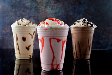 Milkshakes of different flavors on a dark background.
