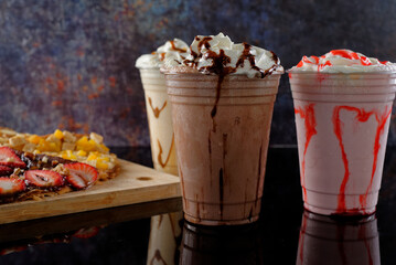 Malted milkshakes of different flavors and crepes. Dark background.