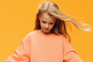 funny emotional girl stands on a bright background and looks down with her hair developing in the...